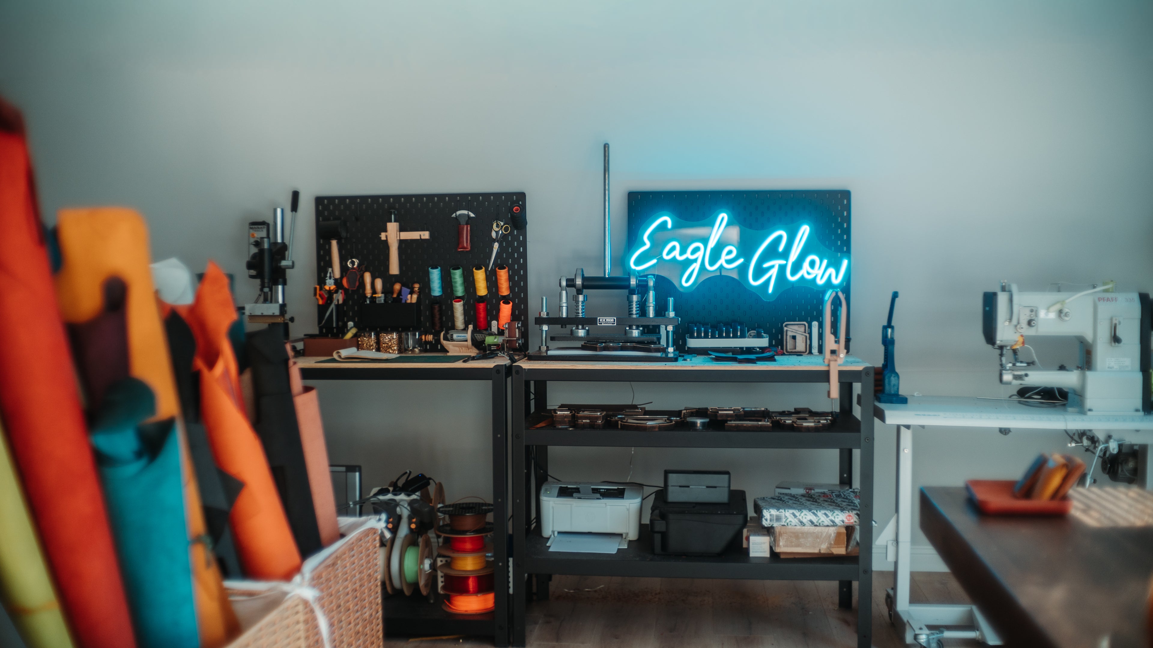 Neon sign reading 'Eagle Glow' in a workshop setting with tools and equipment.